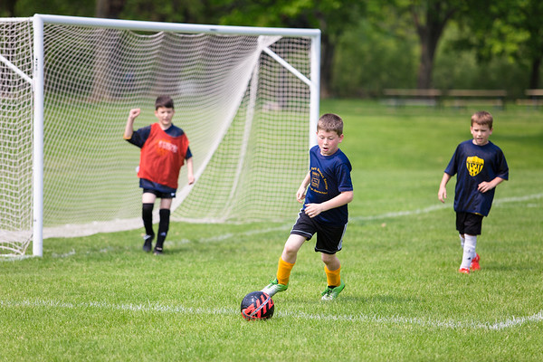 Boys playing soccer in the field and the goalie cheering
